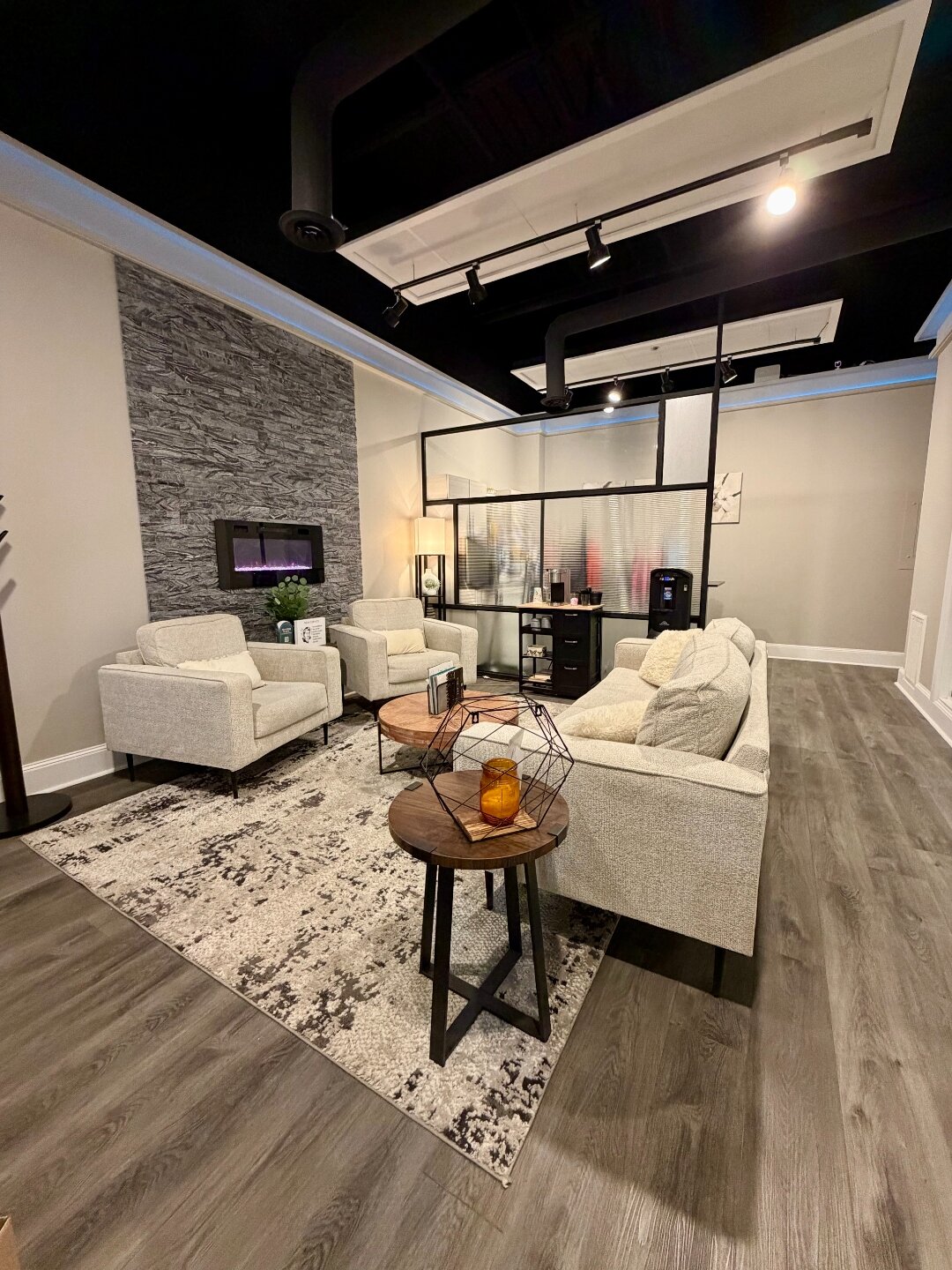 Une Nouvelle Toi waiting room with stone fireplace, plush seating, and warm ambiance